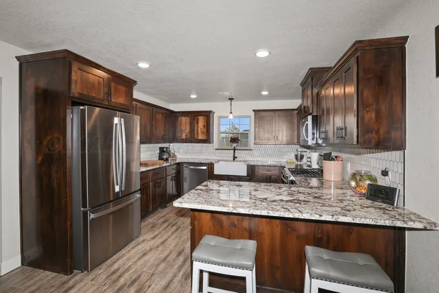 a kitchen with granite countertop kitchen island stainless steel appliances a refrigerator a sink a stove a microwave and dining table