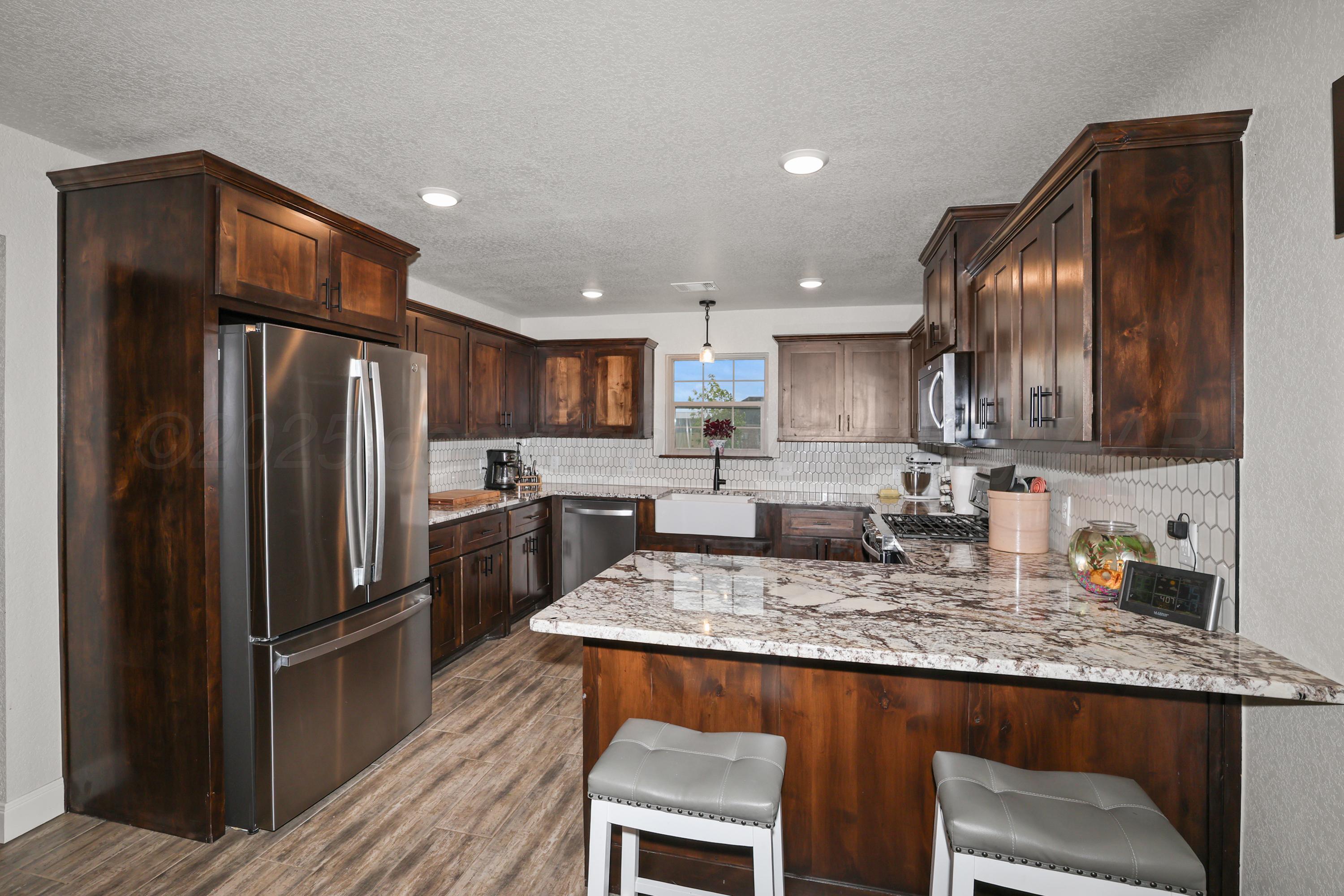17450 Stone Creek Road Amarillo, TX 79124 - Photo 11 of 30 a kitchen with granite countertop kitchen island stainless steel appliances a refrigerator a sink a stove a microwave and dining table