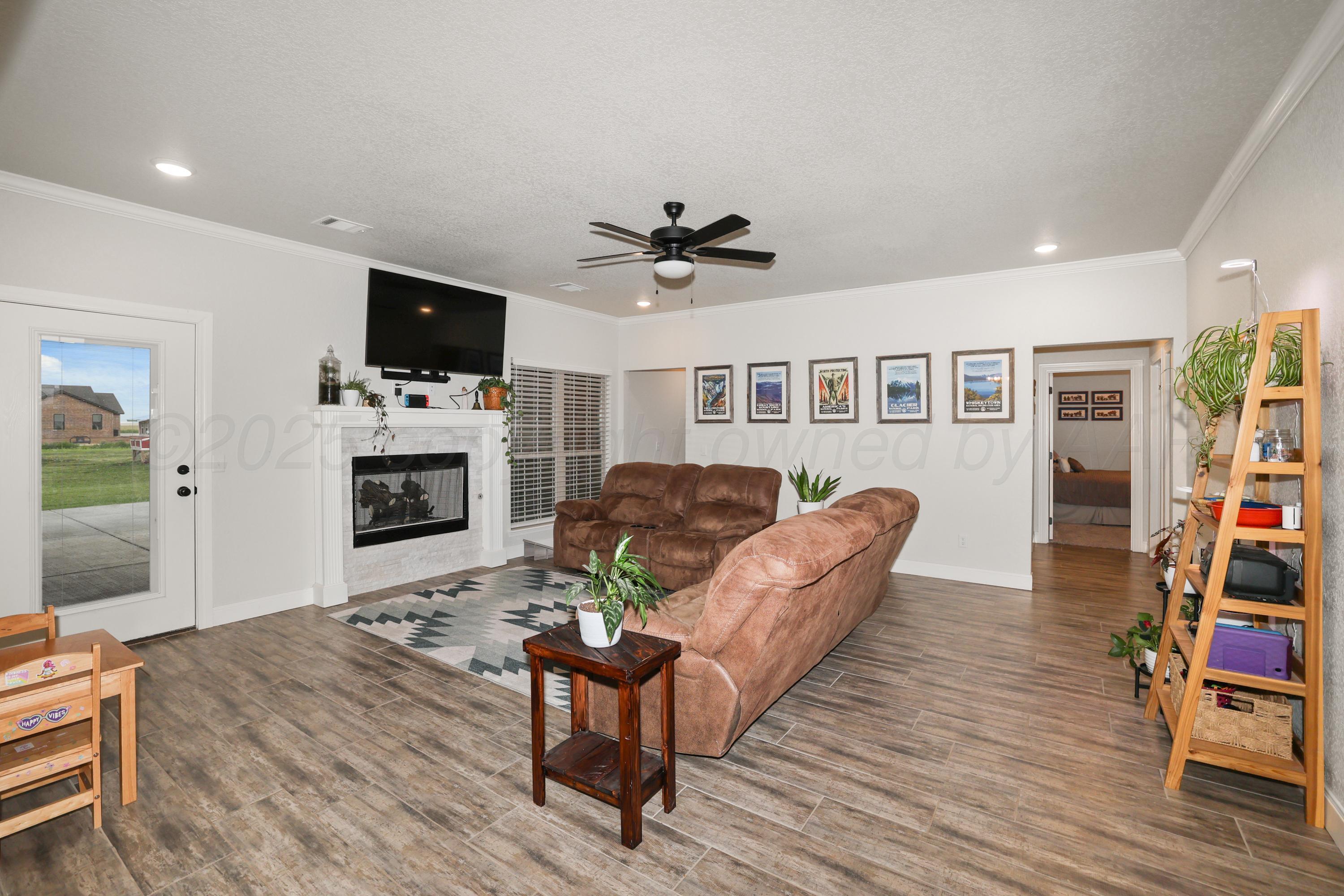 17450 Stone Creek Road Amarillo, TX 79124 - Photo 6 of 30 a living room with furniture a flat screen tv and a fireplace