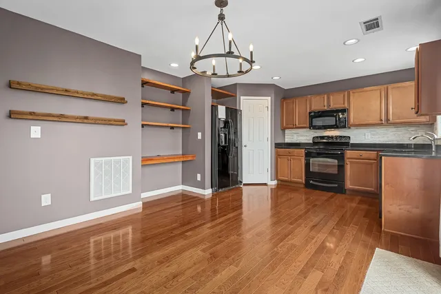 a kitchen with stainless steel appliances granite countertop a refrigerator stove top oven and cabinets