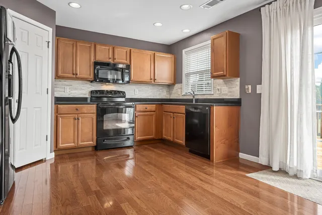 a kitchen with stainless steel appliances granite countertop a stove a sink dishwasher a refrigerator and cabinets with wooden floor