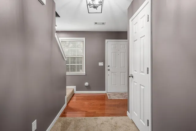 a view of a hallway with wooden floor and a bathroom