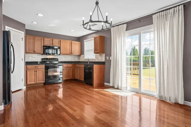 a kitchen with stainless steel appliances granite countertop a refrigerator a stove top oven a sink and dishwasher with wooden floor