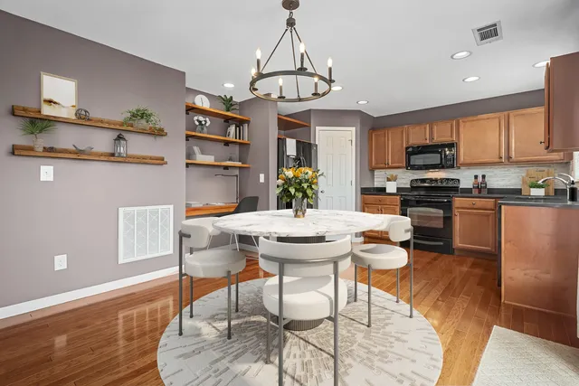 a kitchen with stainless steel appliances kitchen island granite countertop a dining table chairs refrigerator and microwave