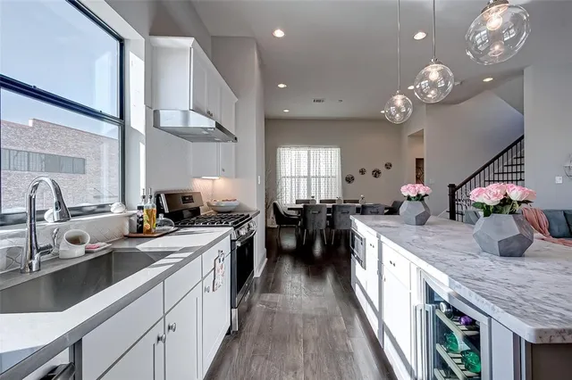 a kitchen with stainless steel appliances granite countertop a sink a stove a refrigerator and island with wooden floor