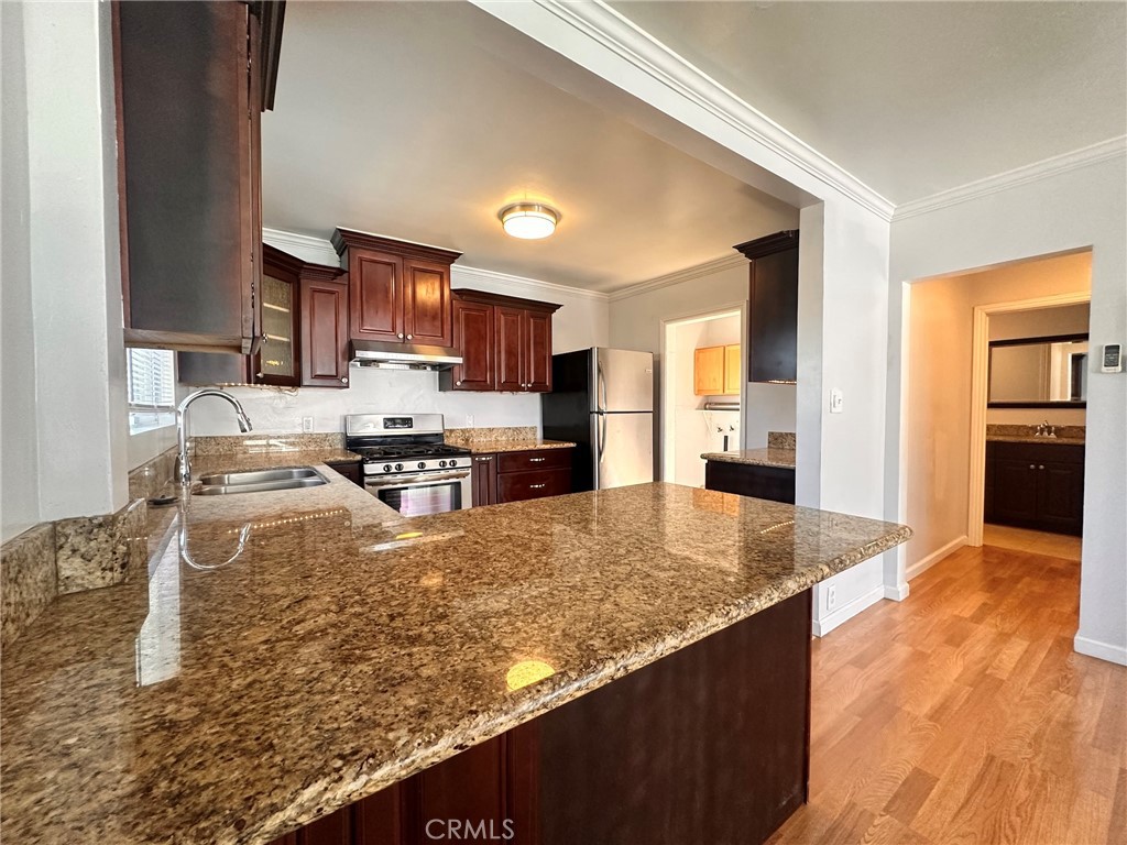 a kitchen with kitchen island granite countertop a sink counter top space appliances and cabinets