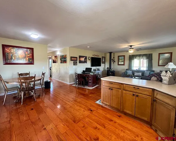 a large kitchen with stainless steel appliances granite countertop a stove a sink a dining table and chairs with wooden floor