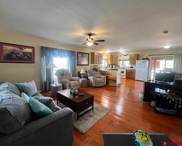 a living room with furniture kitchen view and a chandelier