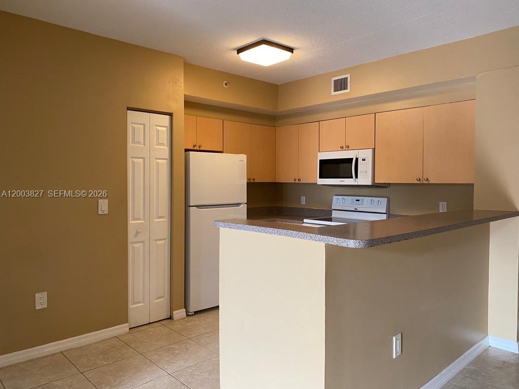 8060 North Nob Hill Road, Unit 203 Tamarac, FL 33321 - Photo 3 of 69 a kitchen with a refrigerator a microwave a sink and a stove