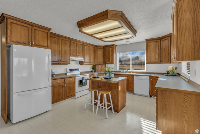 1060 West 2620th Street South Mapleton, UT 84664 - Photo 20 of 87 Kitchen featuring wood finish cabinetry, light flooring, white appliances, a kitchen breakfast bar, and light countertops