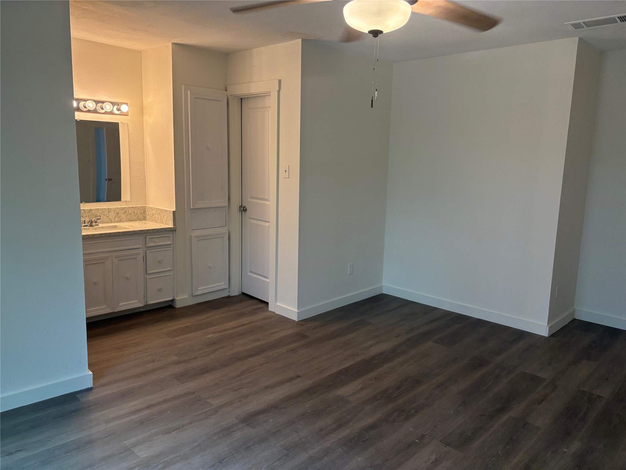 11913 Rennalee Loop Austin, TX 78753 - Photo 20 of 40 A well-lit bedroom with dark wood flooring and a convenient vanity area.