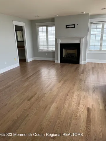 an empty room with wooden floor fireplace and windows