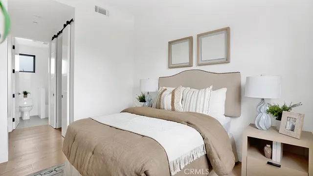 a bedroom with a bed potted plant with the wooden floor