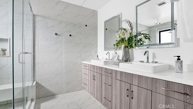 a bathroom with a double vanity sink a mirror and shower