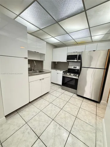 a kitchen with kitchen island a stove a sink a counter top space and cabinets