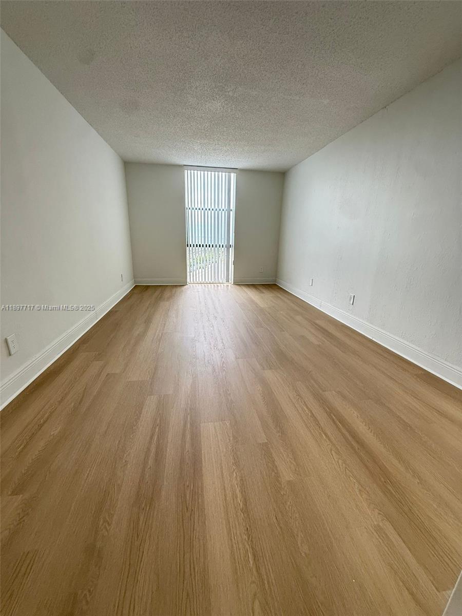 13499 Biscayne Boulevard, Unit 811 North Miami, FL 33181 - Photo 5 of 20 an empty room with wooden floor and windows