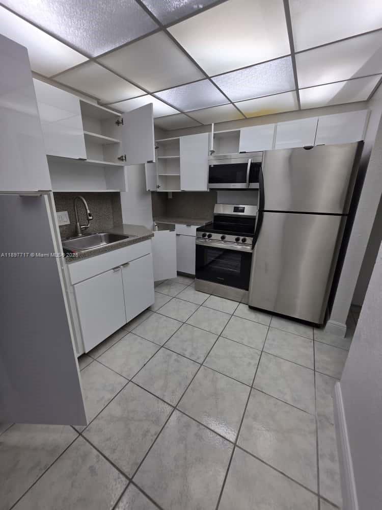 13499 Biscayne Boulevard, Unit 811 North Miami, FL 33181 - Photo 10 of 20 a kitchen with stainless steel appliances granite countertop a refrigerator and a stove top oven