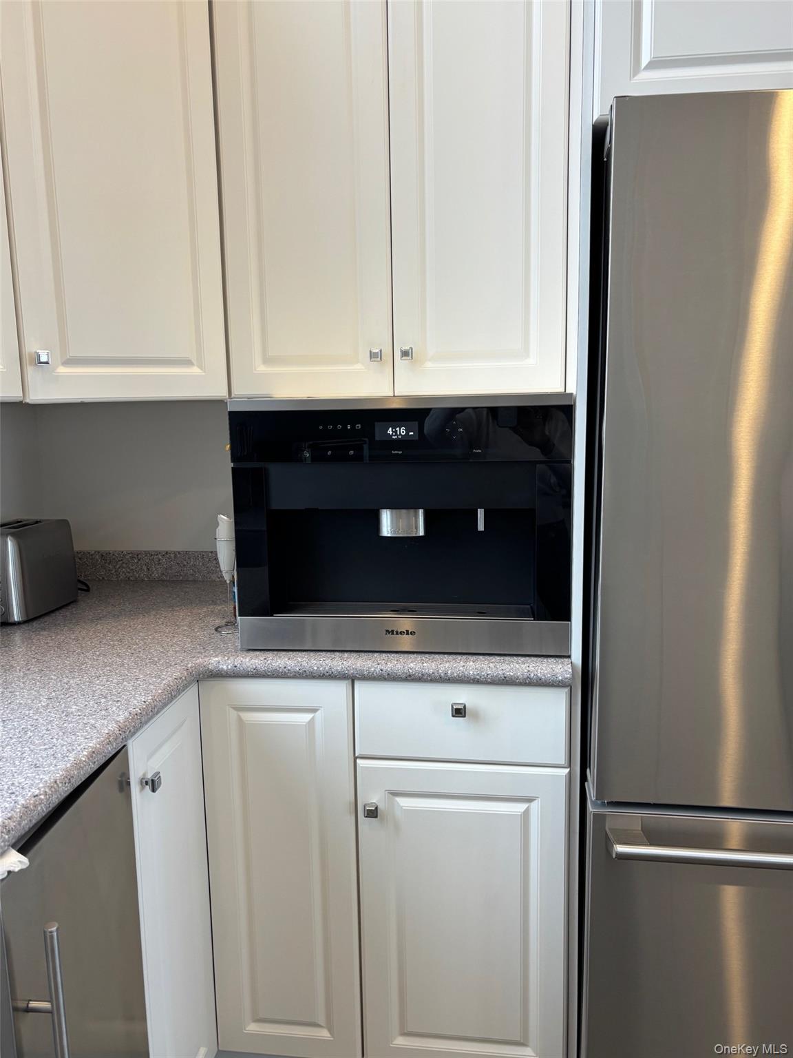 939 Dune Road West Hampton Dunes, NY 11978 - Photo 12 of 25 a kitchen with white cabinets and refrigerator