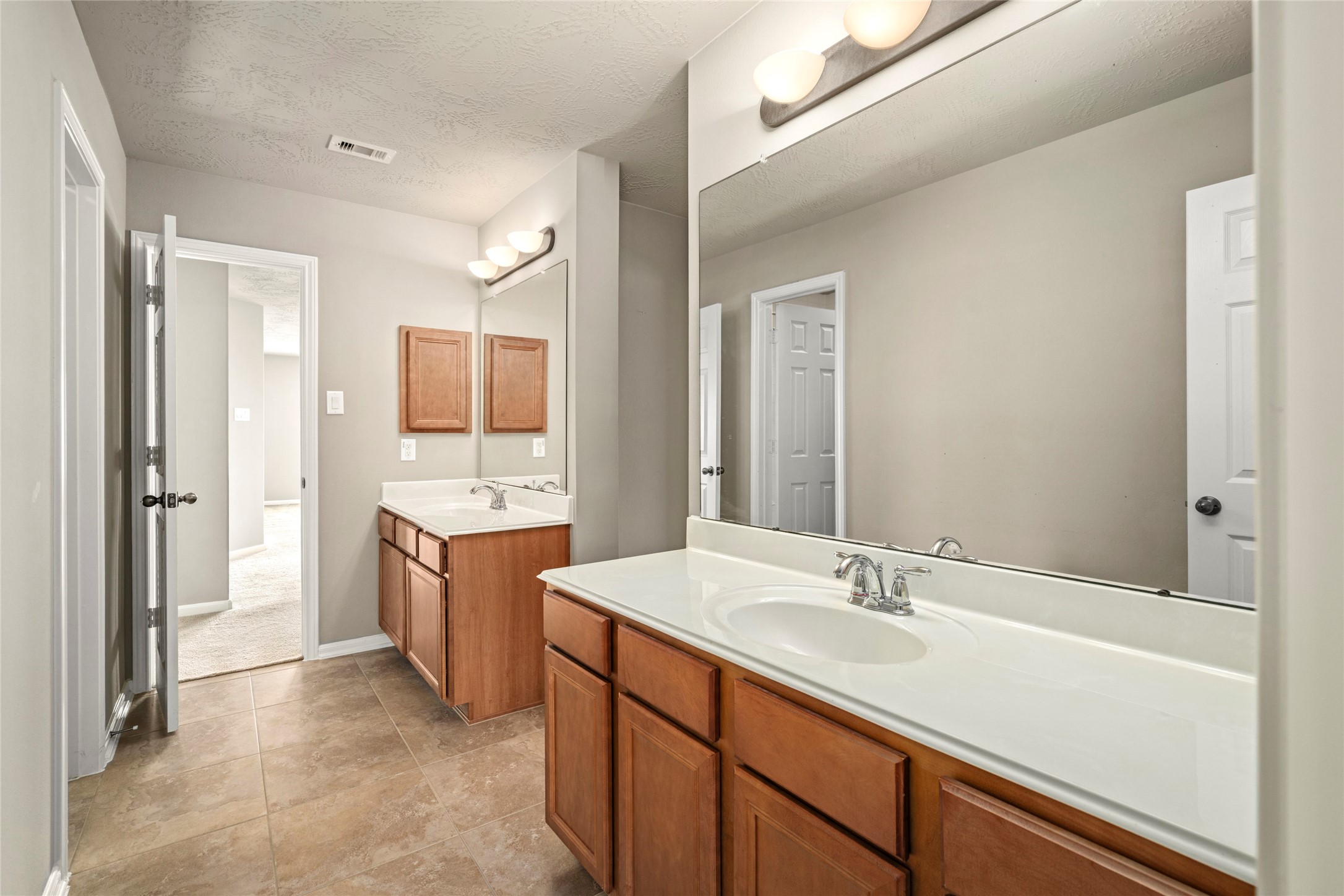 5307 Amber Sky Lane Rosharon, TX 77583 - Photo 36 of 50 A spacious double-vanity bath with rich wood cabinetry, oversized mirrors, and tile flooring serves the upstairs bedrooms with style and function.