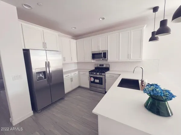 a kitchen with stainless steel appliances granite countertop a refrigerator sink and white cabinets