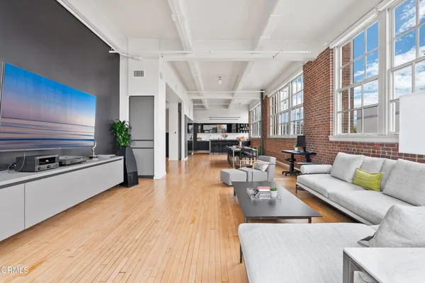 a living room with furniture kitchen view and a wooden floor