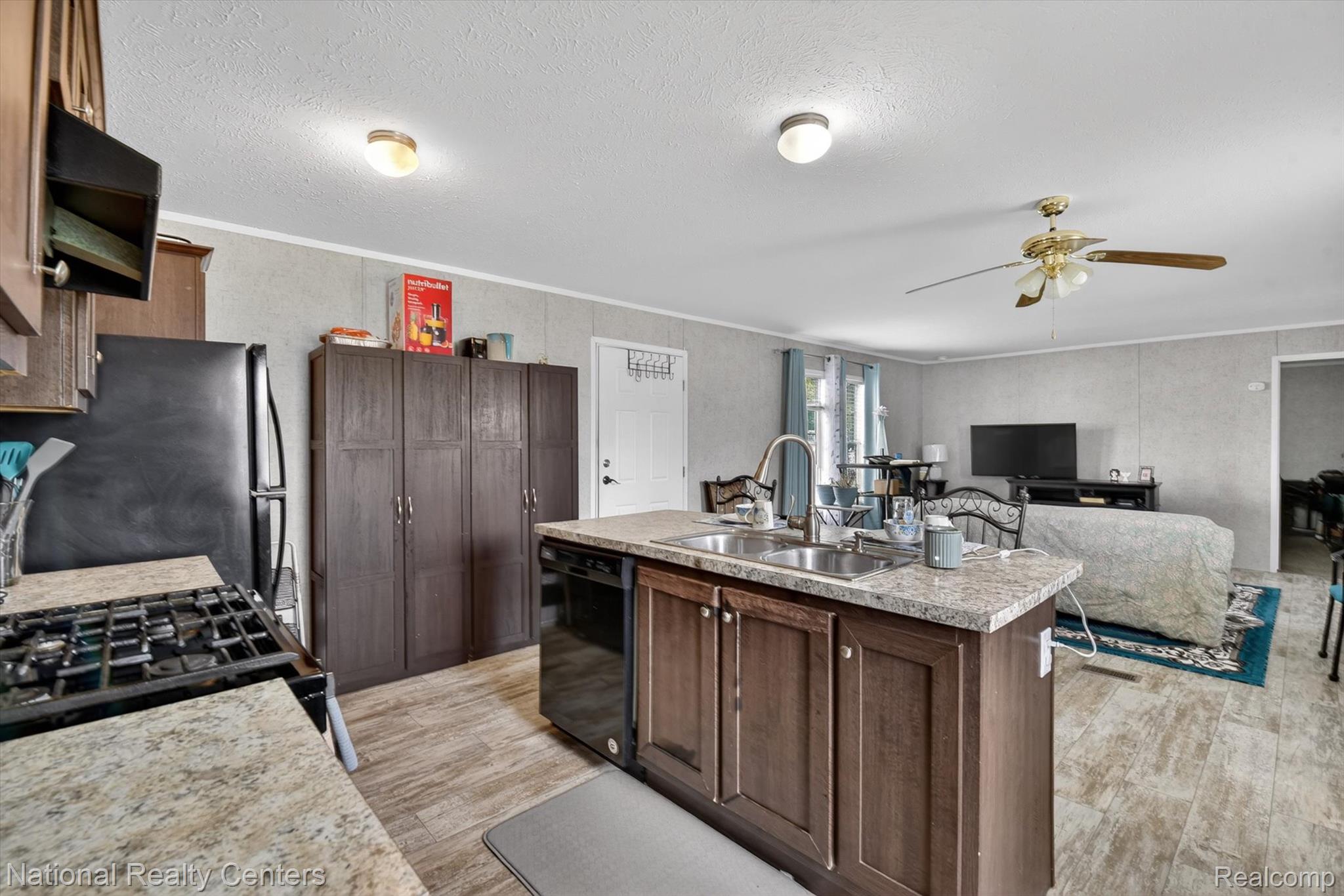 2735 South Wagner Road, Unit 103 Ann Arbor, MI 48103 - Photo 6 of 20 Kitchen featuring light countertops, ceiling fan, a center island with sink, black appliances, and light wood-type flooring