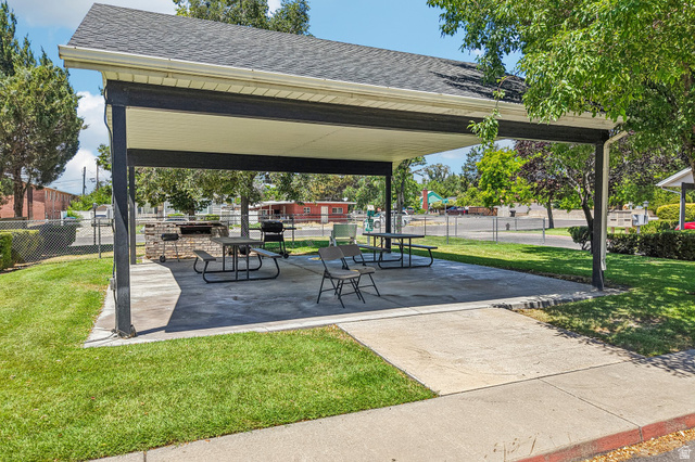 888 600 West, Unit 40 Provo, UT 84604 - Photo 18 of 19 Covered outdoor patio with a concrete slab, integrated brick barbecue, and surrounding manicured lawn