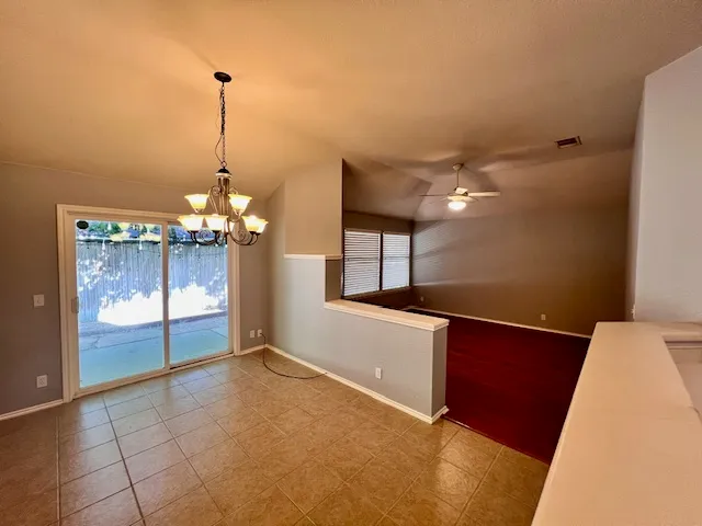 wooden floor in an empty room with a fireplace and a ceiling fan