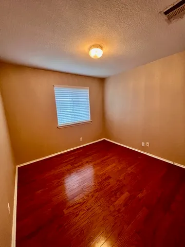 an empty room with wooden floor and window