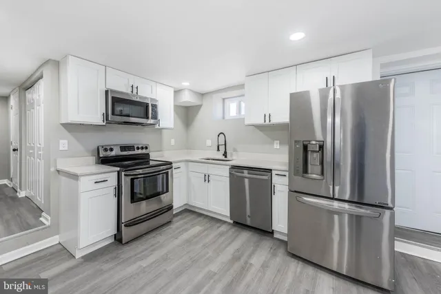 a kitchen with cabinets stainless steel appliances and a window