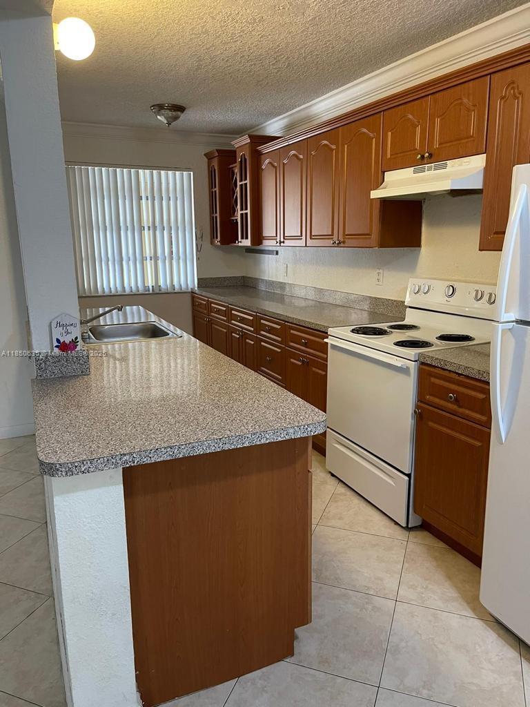 1100 Northeast 1st Court, Unit 106 Hallandale Beach, FL 33009 - Photo 13 of 16 a kitchen with granite countertop stainless steel appliances a stove a sink and a microwave