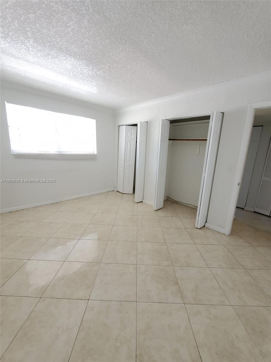1100 Northeast 1st Court, Unit 106 Hallandale Beach, FL 33009 - Photo 3 of 16 an empty room with windows and entrance