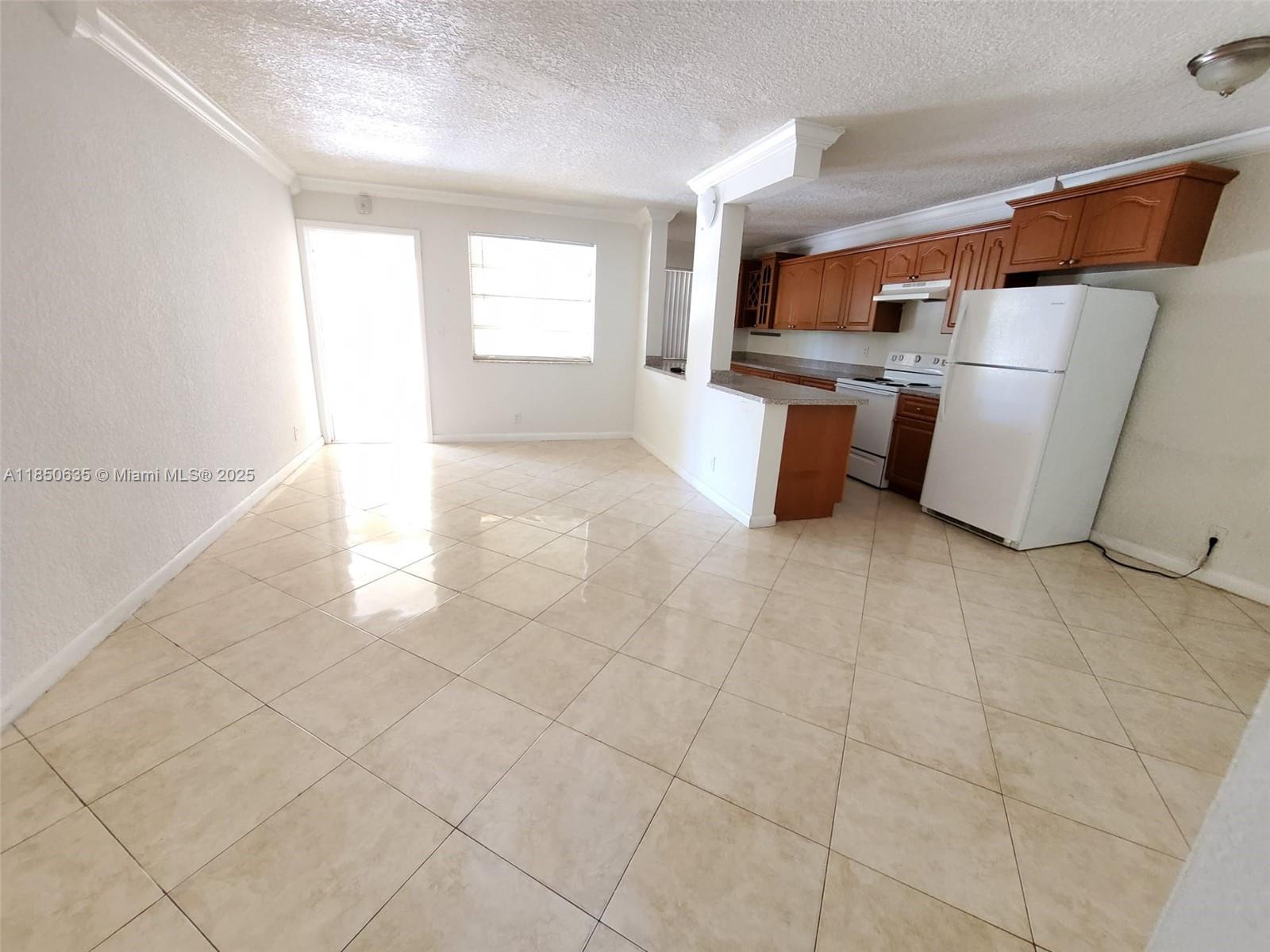 1100 Northeast 1st Court, Unit 106 Hallandale Beach, FL 33009 - Photo 7 of 16 a kitchen with refrigerator and window