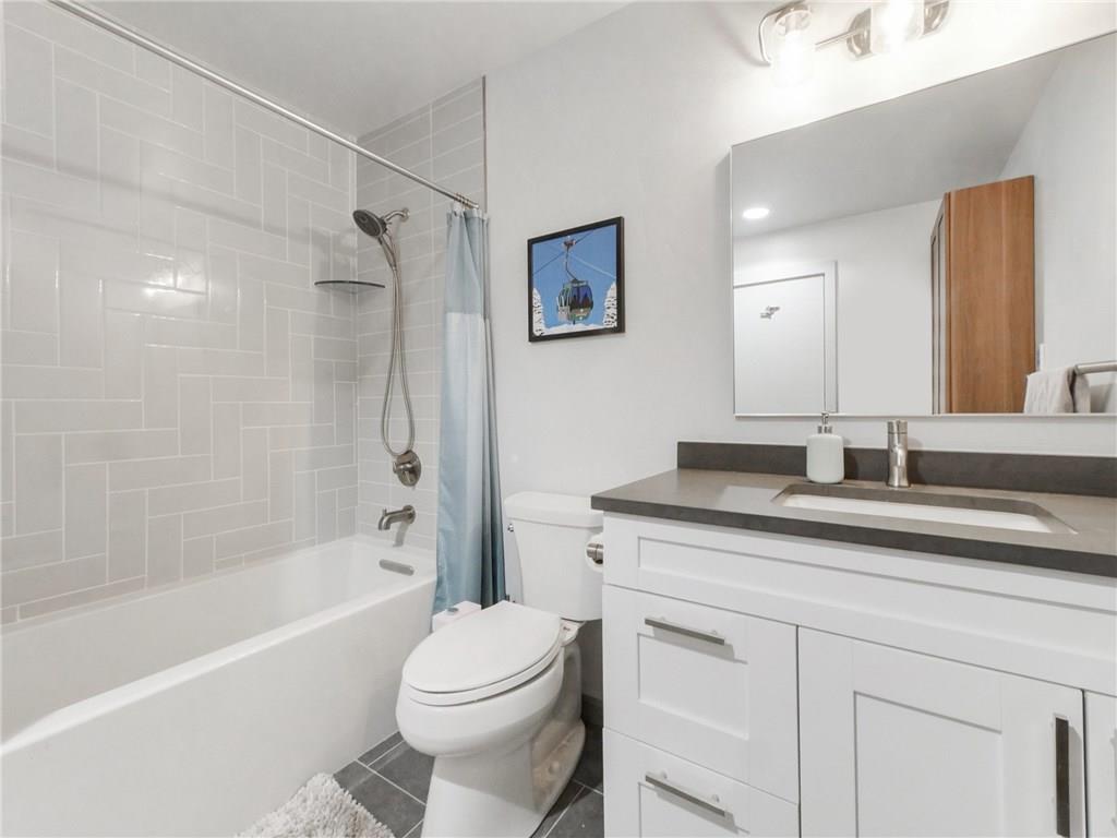 1928 Soda Ridge Road, Unit 1225 Keystone, CO 80435 - Photo 25 of 33 a bathroom with a granite countertop sink a toilet a mirror a bathtub and shower