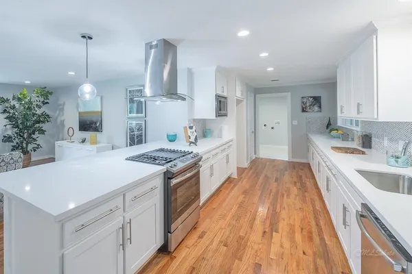 a large kitchen with stainless steel appliances granite countertop a lot of counter space and wooden floors