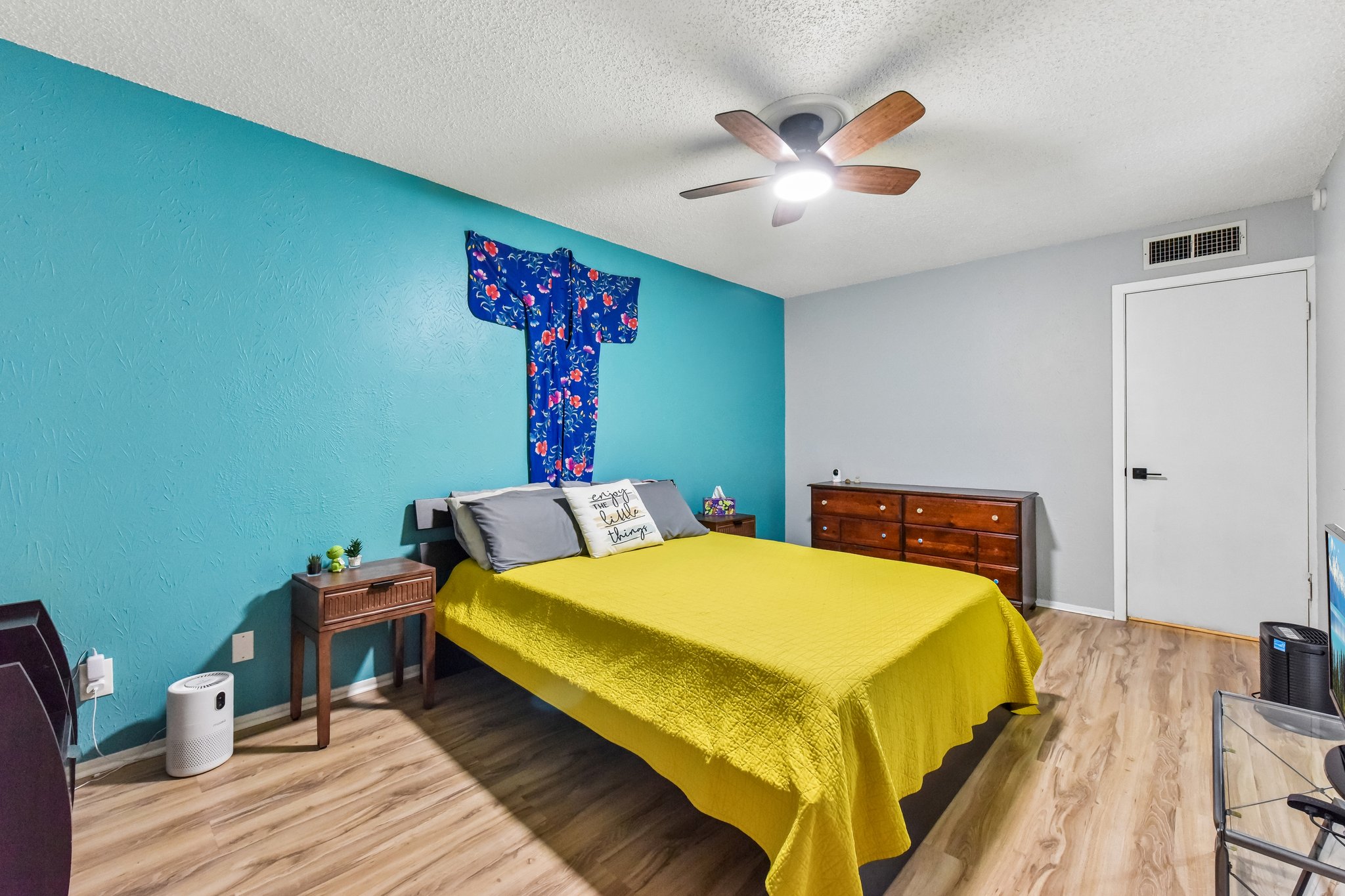 9610 Covey Ridge Lane Austin, TX 78758 - Photo 11 of 22 Bedroom featuring a ceiling fan with integrated lighting, wood-finish flooring, and a textured accent wall