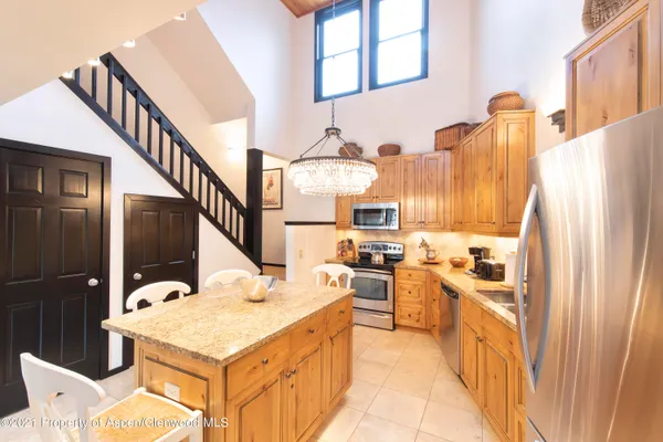 a kitchen with stainless steel appliances kitchen island granite countertop a table chairs in it and a refrigerator