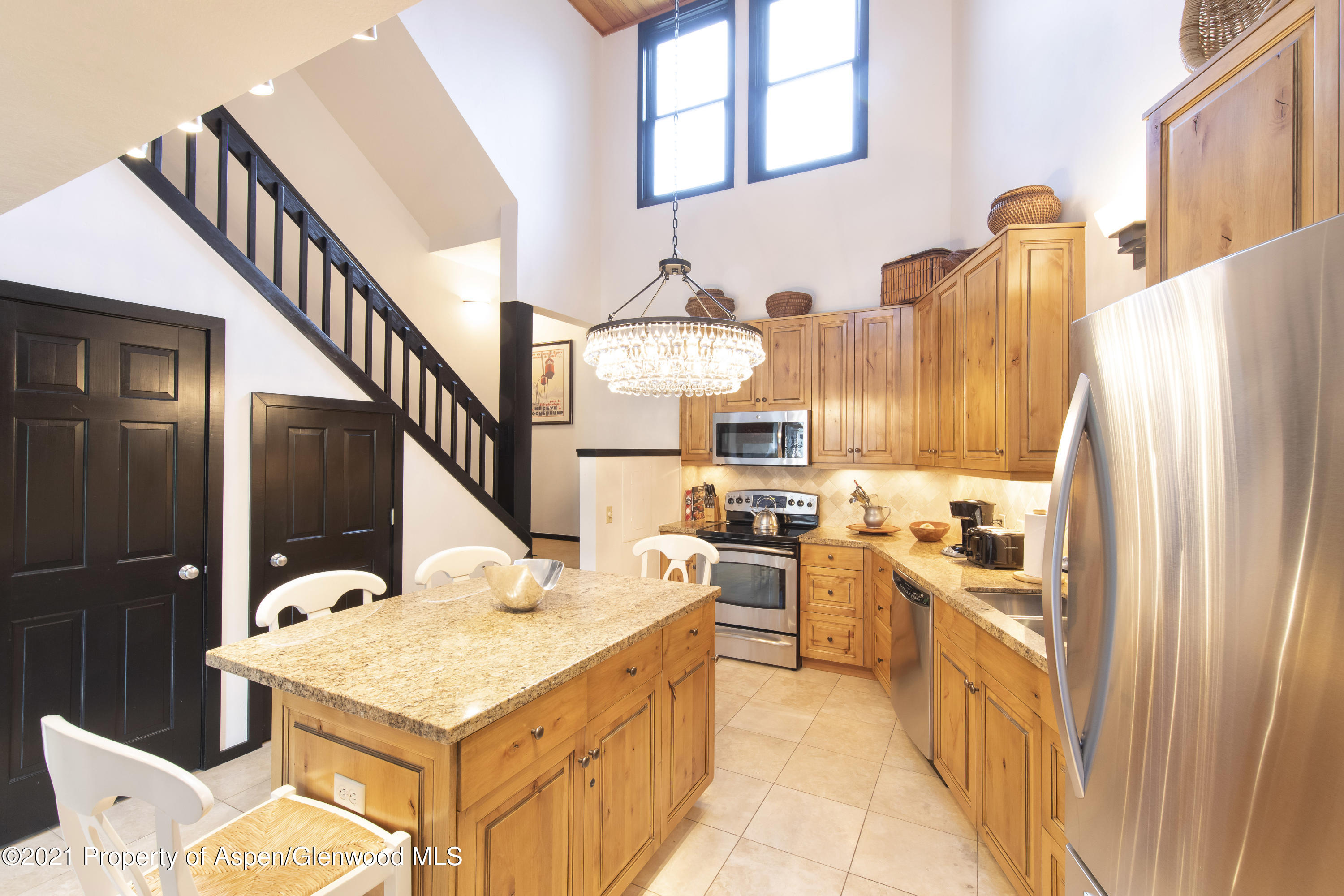 425 Wood Run Road, Unit 36 Snowmass Village, CO 81615 - Photo 1 of 23 a kitchen with stainless steel appliances kitchen island granite countertop a table chairs in it and a refrigerator
