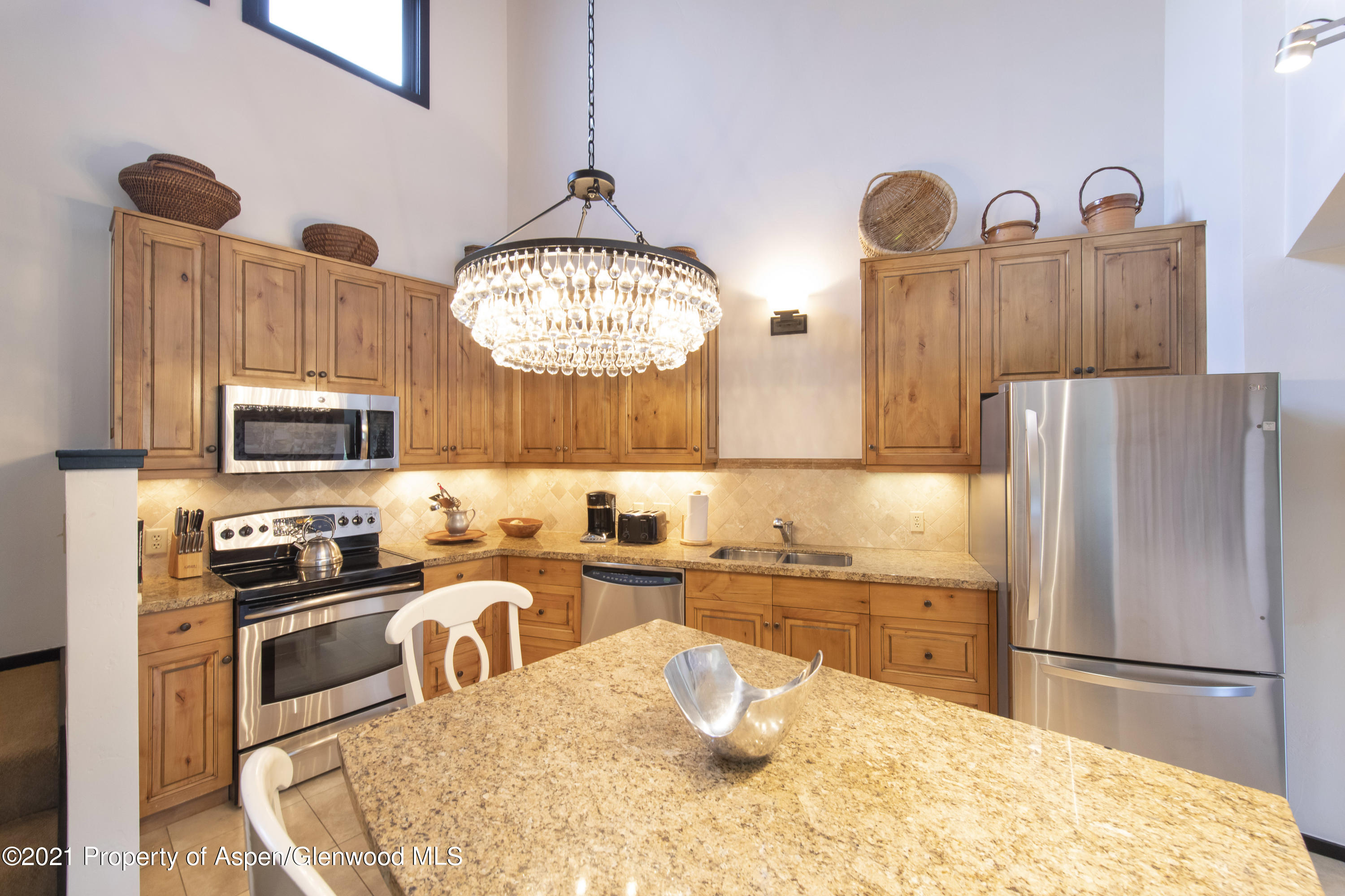 425 Wood Run Road, Unit 36 Snowmass Village, CO 81615 - Photo 3 of 23 a kitchen with stainless steel appliances a refrigerator a stove a sink dishwasher a dining table and chairs with wooden floors
