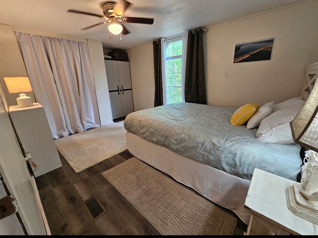 390 Wharf Road Savannah, TN 38372 - Photo 10 of 17 Bedroom featuring wood-finish flooring, a ceiling fan with integrated lighting, and a window with dark drapery