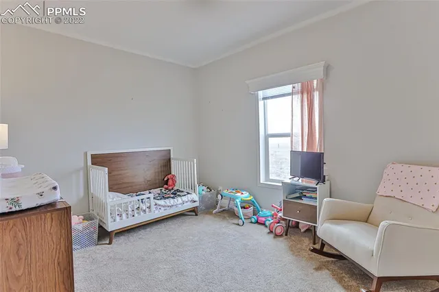 a bedroom with bed a mirror and a flat tv screen on a dresser