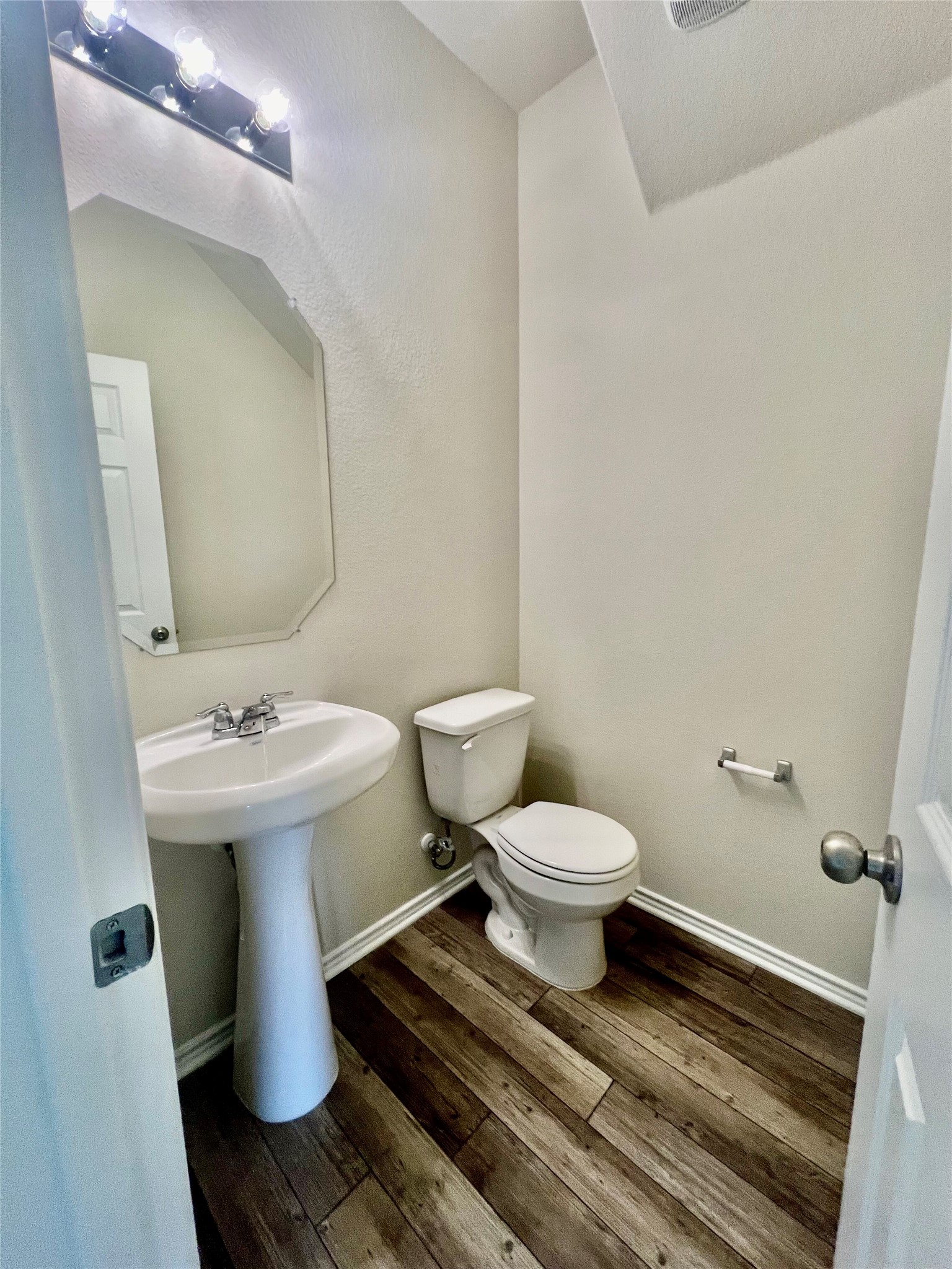 499 Tree Nut Loop Buda, TX 78610 - Photo 11 of 33 A compact guest bath featuring rich wood flooring and a classic pedestal sink.
