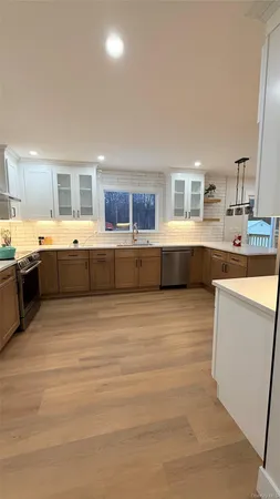 a large white kitchen with kitchen island granite countertop wooden cabinets and stainless steel appliances
