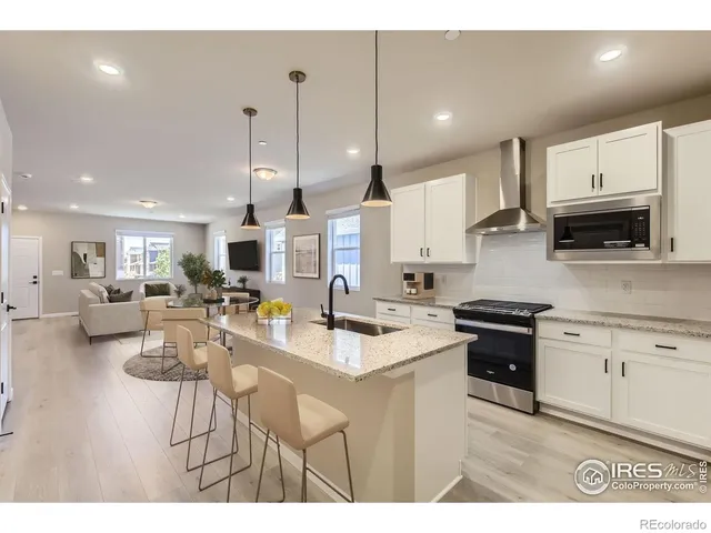 a kitchen with stainless steel appliances granite countertop a stove a sink a oven a dining table and chairs with wooden floor