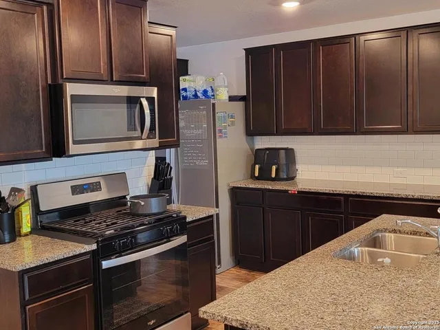a kitchen with granite countertop stainless steel appliances and wooden cabinets