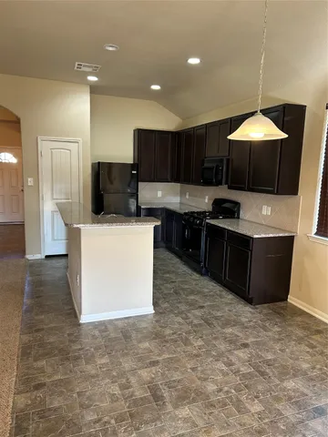 a kitchen with stainless steel appliances a stove a refrigerator a sink a microwave oven and a dining table with wooden floor