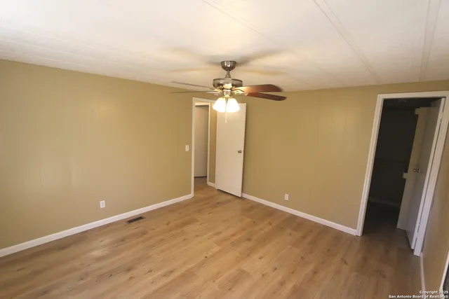 a view of a room with wooden floor and a ceiling fan