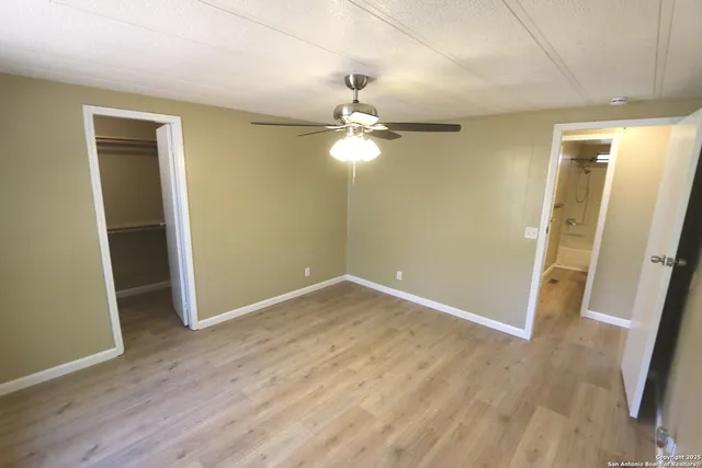an empty room with wooden floor and a ceiling fan