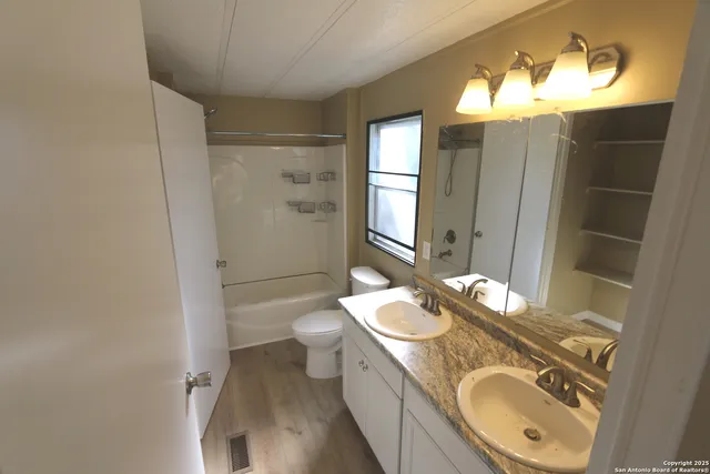 a bathroom with a granite countertop double vanity sink mirror and toilet