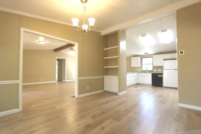 a view of a hallway with wooden floor and a kitchen